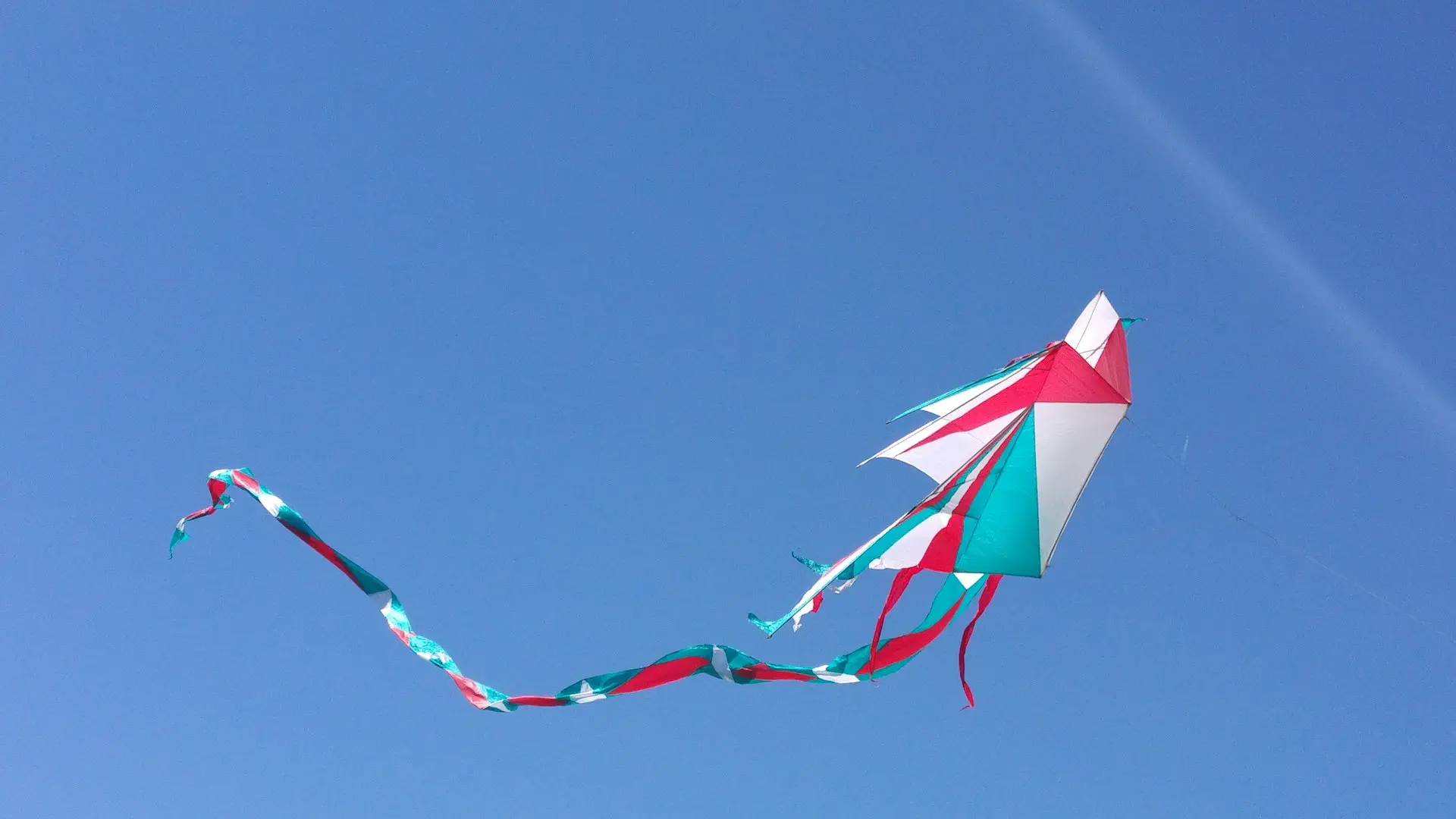 photo of white, blue, and red kite under blue sky